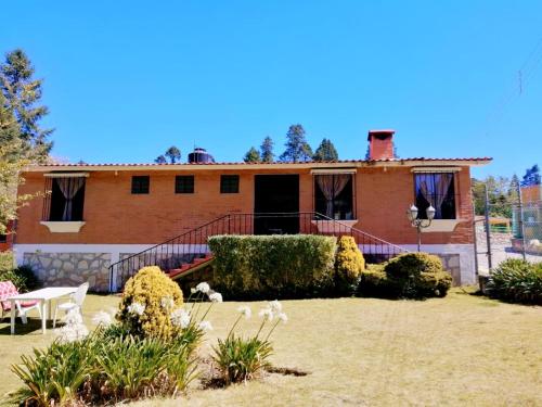 a brick house with a yard with bushes and flowers at La Cabaña de Tano in Mineral del Monte