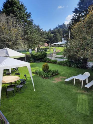 a lawn with a table and chairs and a white tent at La Cabaña de Tano in Mineral del Monte