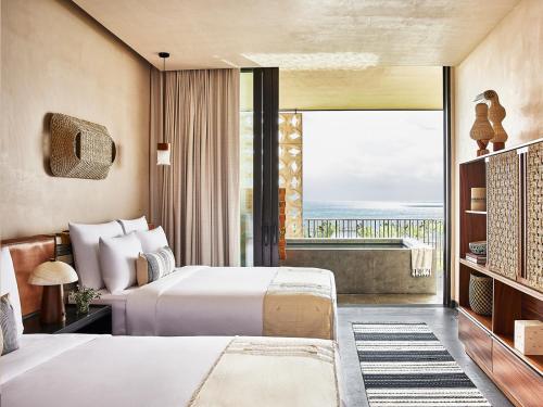 a bedroom with two beds and a large window at Etéreo, Auberge Collection in Playa del Carmen