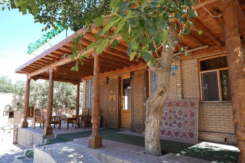 a wooden pergola on a house with a table and chairs at Shaherezada Boutique Hotel in Khiva