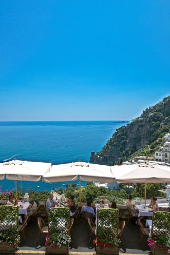 a group of people sitting at tables under white umbrellas at Hotel Villa Gabrisa in Positano