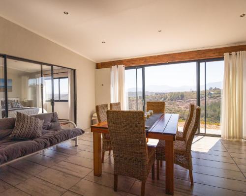 a dining room with a table and chairs and a couch at SERENE VIEW, simply beautiful accommodation in Groot Brak Rivier