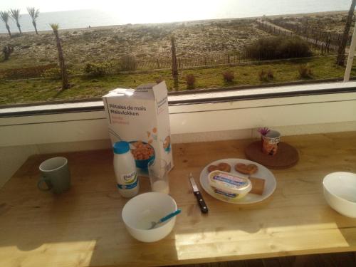 a box and a plate of food on a table with a window at T3 avec magnifique vue mer in Le Barcarès