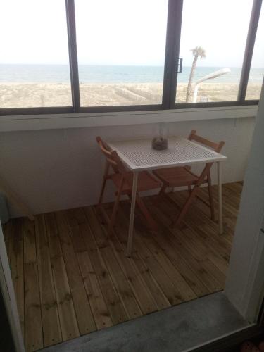 a table and chairs in a room with a view of the beach at T3 avec magnifique vue mer in Le Barcarès