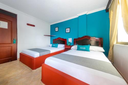 Duas camas num quarto com uma parede azul em Ayenda La Terraza Popayán em Popayán