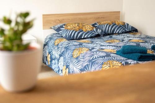 a bed with a blue and yellow blanket and pillows at studio cosy TV WIFI confortable et chaleureux in Gaillon
