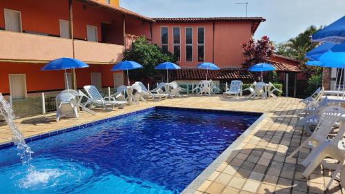 a pool with chairs and umbrellas in front of a building at Pousada Estalagem Da Serra in Serra do Cipo