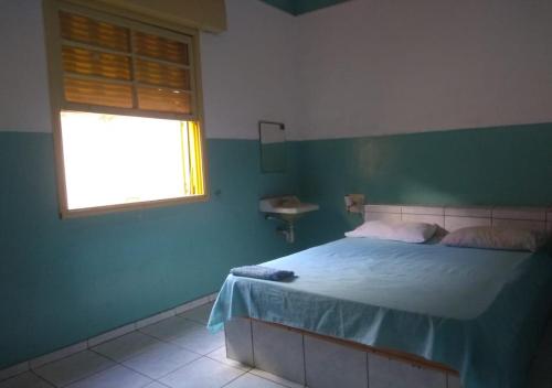 um quarto com uma cama grande e uma janela em Rex Hotel em Marília
