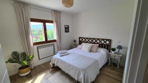 a bedroom with a white bed and a window at Apartamento Mirador Valdeiglesias in Pelayos de la Presa
