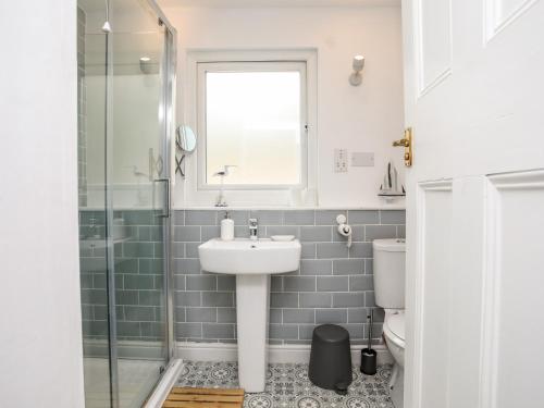 een badkamer met een wastafel en een glazen douche bij Bwthyn Siliwen Old Bath House in Bangor