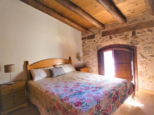 1 dormitorio con cama y pared de piedra en Casa Tropiet en Beceite