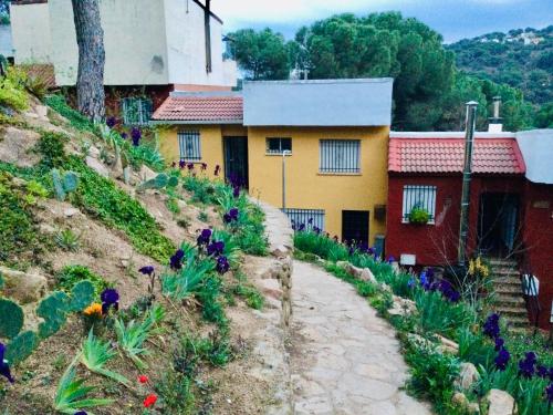 uma casa ao lado de uma colina com flores em La casa del pantano de San Juan em San Martín de Valdeiglesias