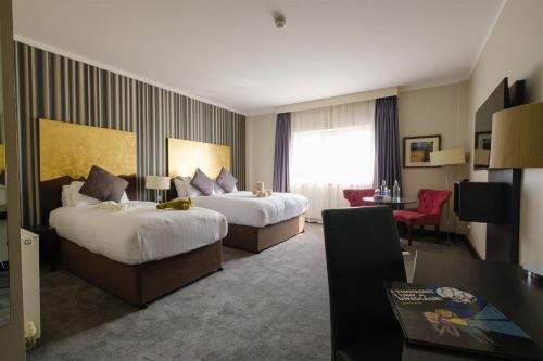 a hotel room with two beds and a desk at Talbot Hotel Carlow in Carlow