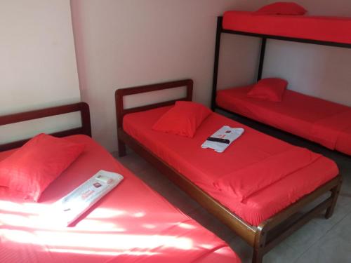 a room with two beds with red sheets and a remote control at Hotel Panorama Neiva in Neiva
