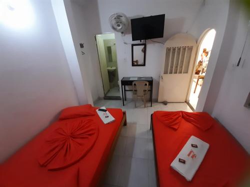 a bedroom with two red beds and a television at Hotel Panorama Neiva in Neiva
