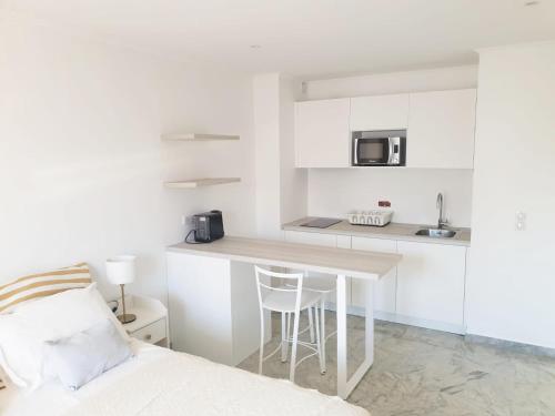 una pequeña cocina blanca con una mesa y una cama en Beautiful T1 with sea view en Niza