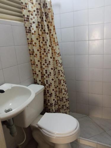a bathroom with a toilet and a sink and a shower curtain at Hotel Panorama Neiva in Neiva