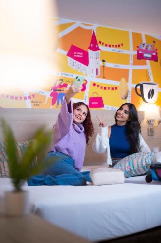 two girls sitting on a bed with their hands in the air at Centro by Casa Andina Miraflores in Lima