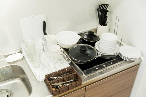a kitchen counter with a stove with plates and dishes at SG RESIDENCE INN HAKATA - Vacation STAY 61970v in Fukuoka