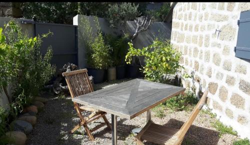 drewniany stół i dwa krzesła siedzące obok ściany w obiekcie Chez Robert et Sylvie w mieście Pianottoli-Caldarello
