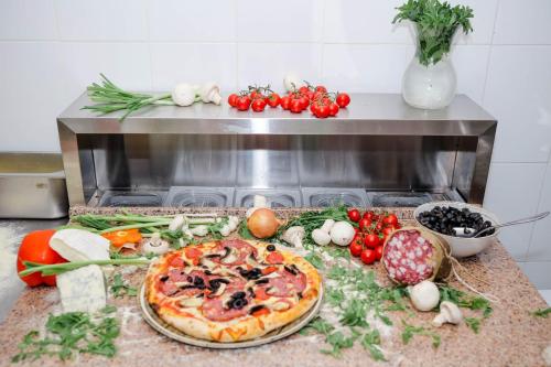a pizza sitting on top of a counter with vegetables at Pensiune Restaurant Select in Băile Herculane