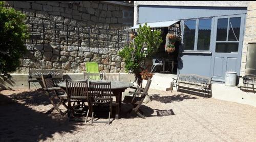 einen Tisch und Stühle in einem Hof mit einer Steinmauer in der Unterkunft Chez Robert et Sylvie in Pianottoli-Caldarello