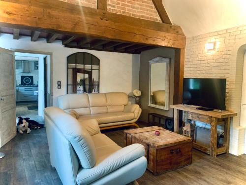 ein Wohnzimmer mit einem Sofa und einem TV in der Unterkunft Villa SAINT CHRISTOPHE de FIRFOL in Firfol