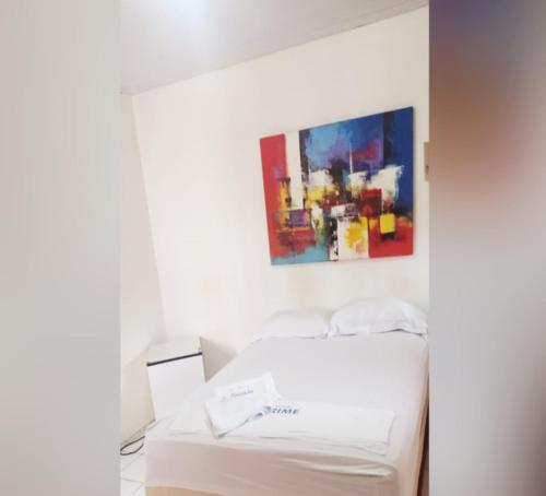 uma cama branca num quarto com uma pintura na parede em pousada Sol e Praia em Fortaleza