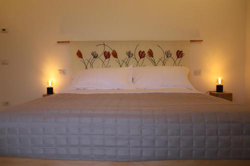 a bedroom with a large bed with two candles on it at La casina col fico in San Vito Rimini