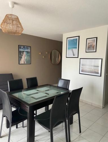 une salle à manger avec une table en verre et des chaises noires dans l'établissement Appartement de standing au port de l’Aiguillon, à Arcachon
