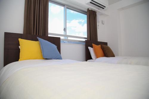 two beds with colorful pillows in a room with a window at Guest room WES - Vacation STAY 54452v in Uruma