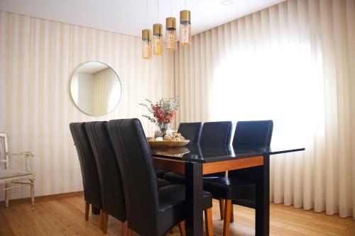a dining room table with black chairs and a mirror at Helena's Family House in Pinhão