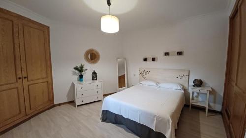 een slaapkamer met een wit bed en een houten kast bij Casa Buzones in Toledo