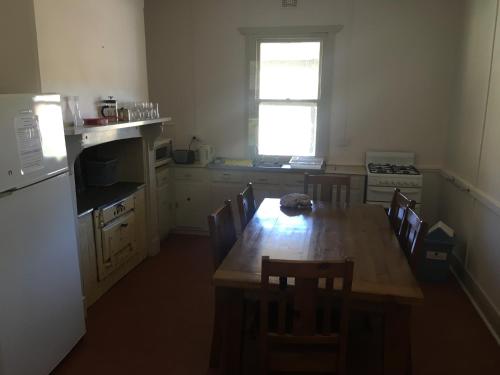 a kitchen with a wooden table with chairs and a window at Old Homestead - The Dutchmans Stern Conservation Park in Quorn