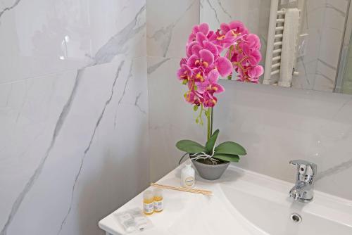 a vase of pink flowers sitting on a bathroom sink at Red Queen Naples in Naples