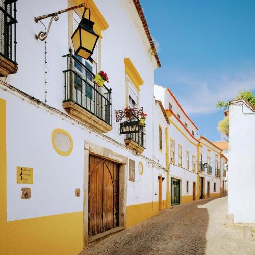 a street in an old town with yellow and white buildings at Almoura Ladeira in Évora