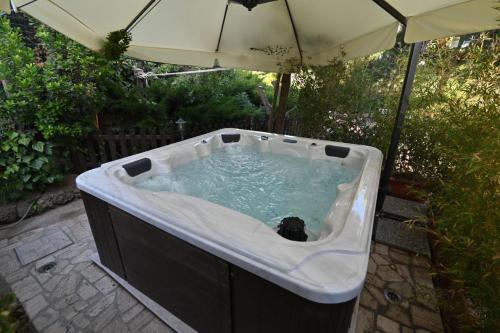 a hot tub with an umbrella in a yard at Agriturismo le Fontane - Lago di Bolsena in Grotte di Castro