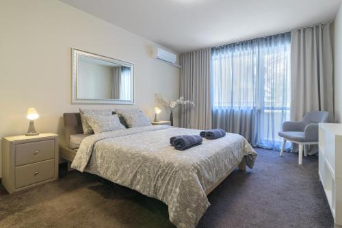 a bedroom with a bed and a chair and a mirror at МareliS Luxe Port Apartment in Varna City