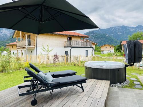 a chair and an umbrella on a deck with a hot tub at Chalet Charivari Inzell, Inzell in Inzell