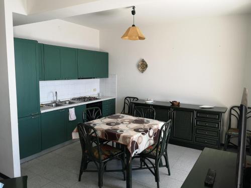 a kitchen with green cabinets and a table with chairs at Appartamento Di Bella simil villetta panoramicissimo in Letojanni