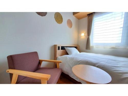 a bedroom with a bed and a chair and a table at ｂｕｓｉｎｅｓｓ&ａｃｔｉｖｉｔｙ ｃｈａｎｖｒｅ - Vacation STAY 64311v in Tochigi