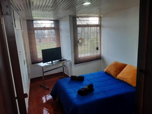 a bedroom with a blue bed and a television at Habitacion con baño compatido en casa de familia en Corferias, Quinta Paredes, Embajada Americana in Bogotá