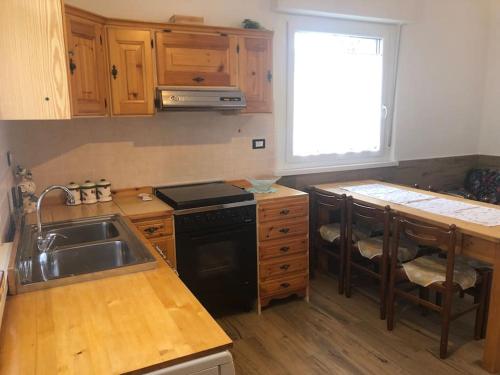 a kitchen with a sink and a stove at Appartamento luminoso, giardino, vista Dolomiti. in Baselga di Pinè
