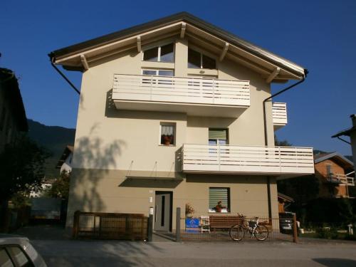 a building with a balcony and a bike in front of it at Appartamento luminoso, giardino, vista Dolomiti. in Baselga di Pinè