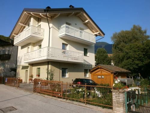 una casa con balcones blancos y una valla delante de ella en Appartamento luminoso, giardino, vista Dolomiti., en Baselga di Pinè