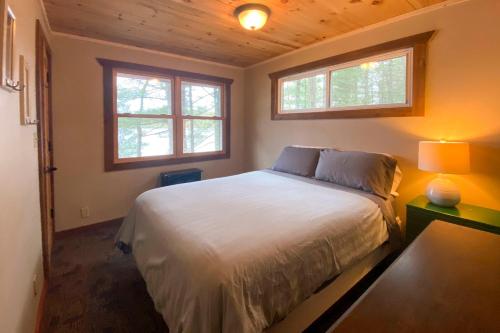 um quarto com uma cama branca e 2 janelas em Burns Lake Cabin with Dock, Fire Pit, Rowboat and More em Little Round Lake