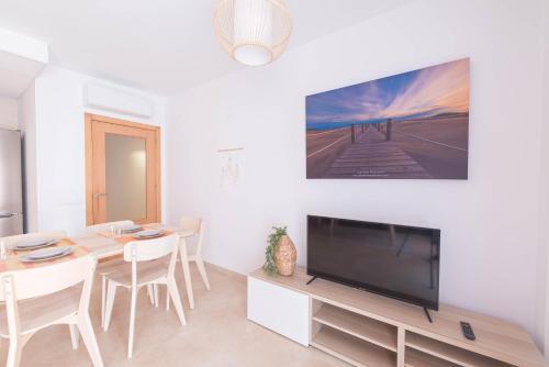 a living room with a dining table and a flat screen tv at El Rincón de Elena Delta del Ebro in Els Muntells