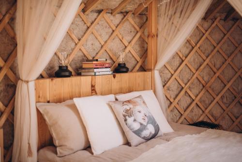 a room with a bed with pillows and books at VasaRojaus Jurta in Birštonas