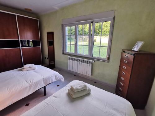 a bedroom with two beds and a window at Casa da Pioxa in Camariñas