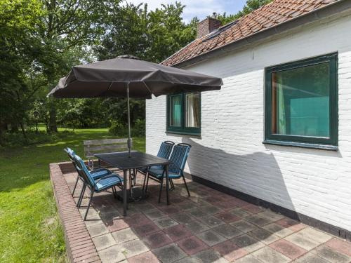 een tafel en stoelen met een parasol op een patio bij Attractive vacation home with spacious garden in Vrouwenpolder